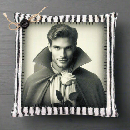Decorative pillow with a black and white portrait of a handsome young vampire in a cape holding a rose, on a striped background.