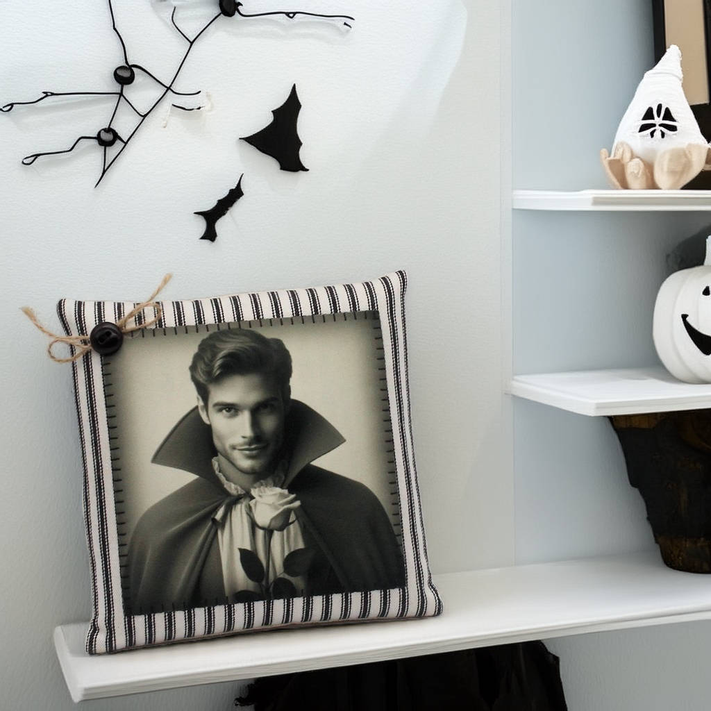 Decorative pillow with a black and white design of a handsome young vampire in a cape on a shelf.