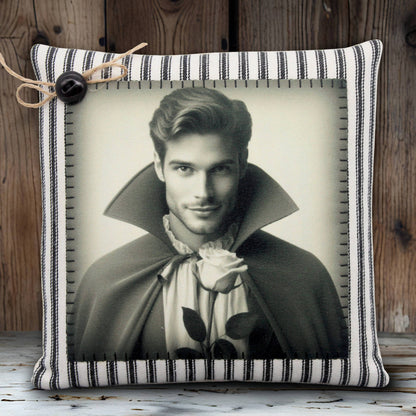 Decorative pillow with a black and white portrait of a handsome young vampire in a cape holding a rose, on a striped background.