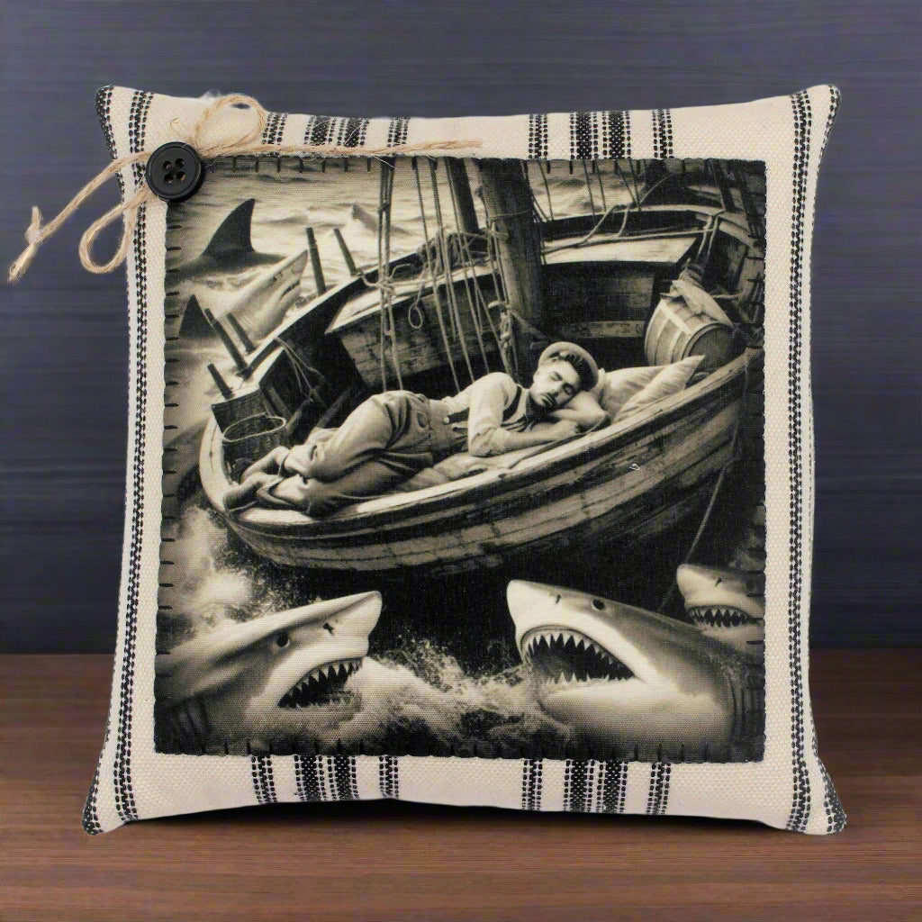 Pillow with a black and white illustration of a man in a boat surrounded by sharks.
