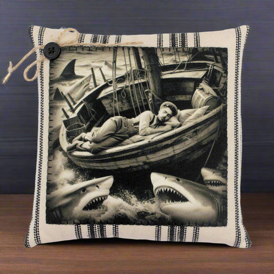 Pillow with a black and white illustration of a man in a boat surrounded by sharks.