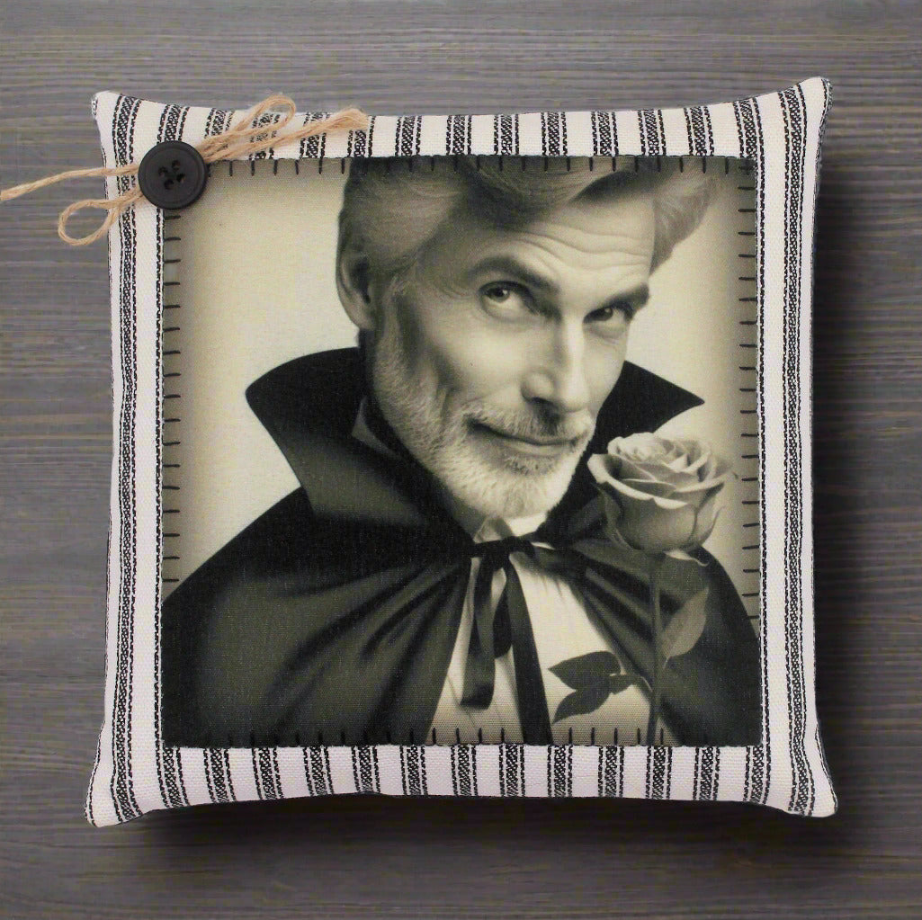 Pillow with a black and white portrait of a handsome vampire holding a rose, framed by a striped border.