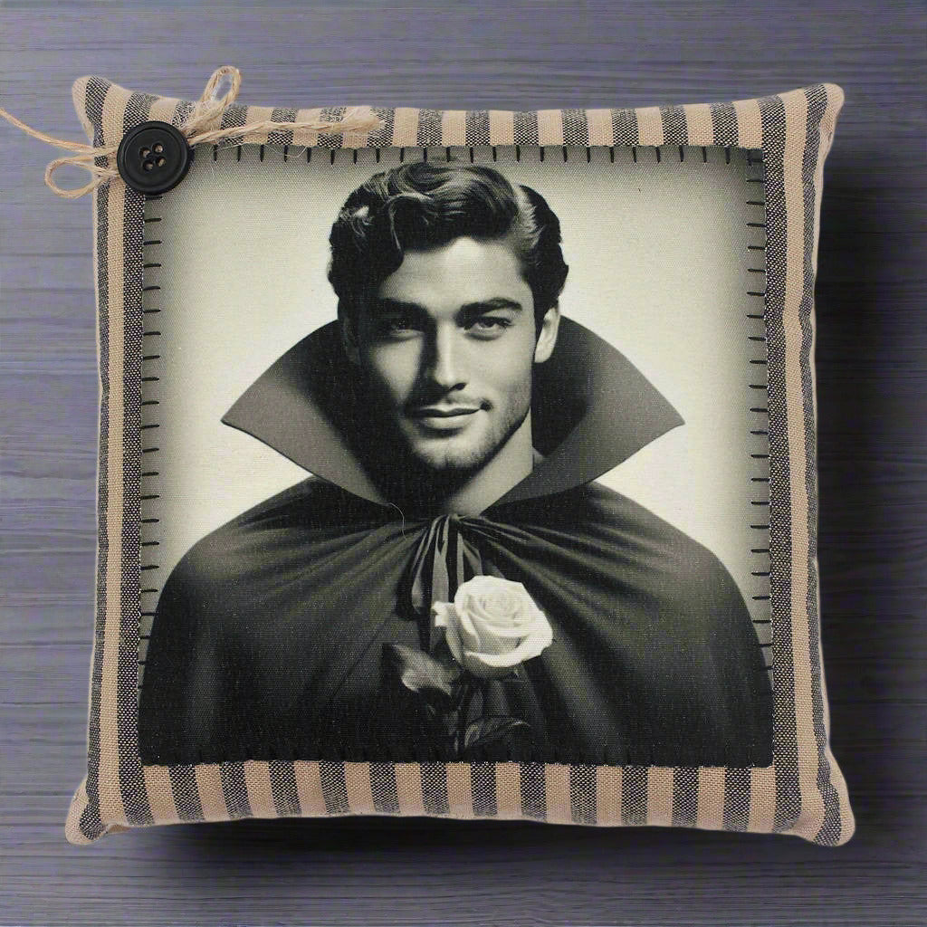 Pillow with a black and white portrait of a handsome young vampire in a cape holding a rose, framed by a striped border.