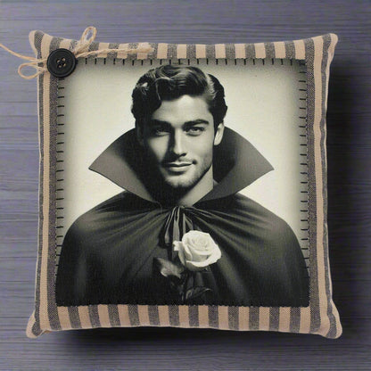 Pillow with a black and white portrait of a handsome young vampire in a cape holding a rose, framed by a striped border.