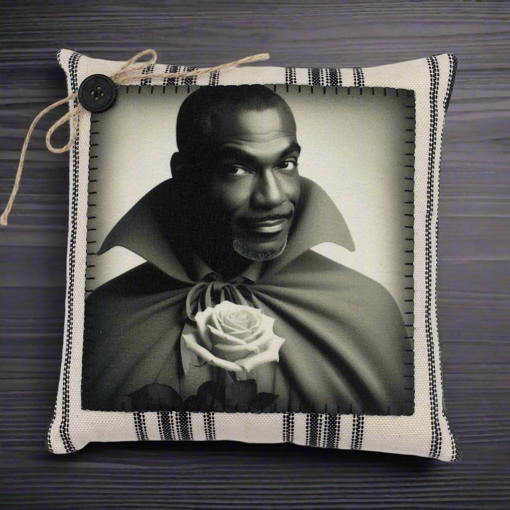 Pillow with a black and white portrait of a handsome vampire holding a rose, framed by decorative fabric.