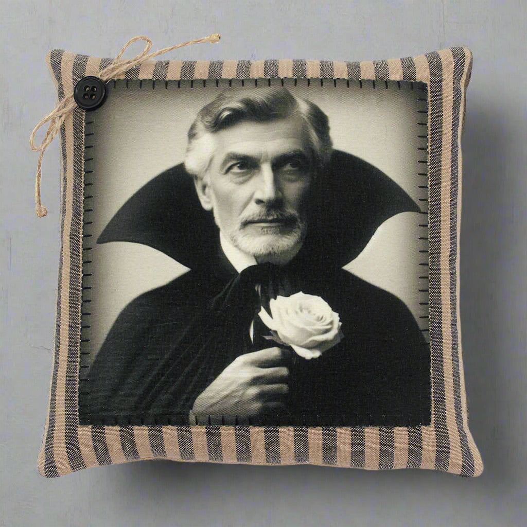 Pillow with a vintage-style portrait of a vampire in a dark robe holding a white rose, framed by striped fabric.
