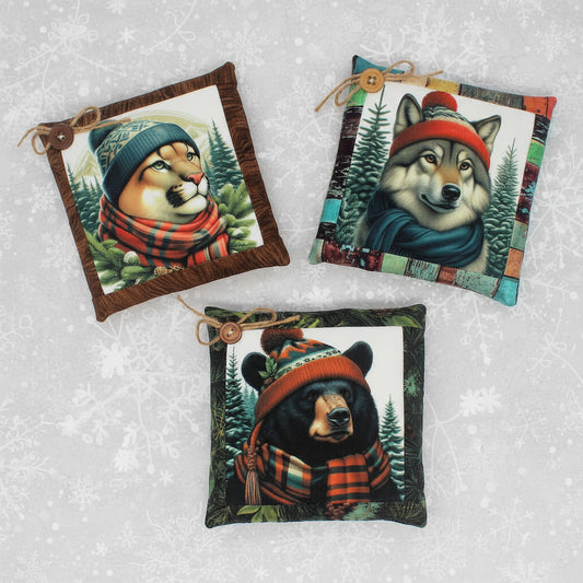 Three decorative pillows featuring animals wearing hats and scarves on a white background