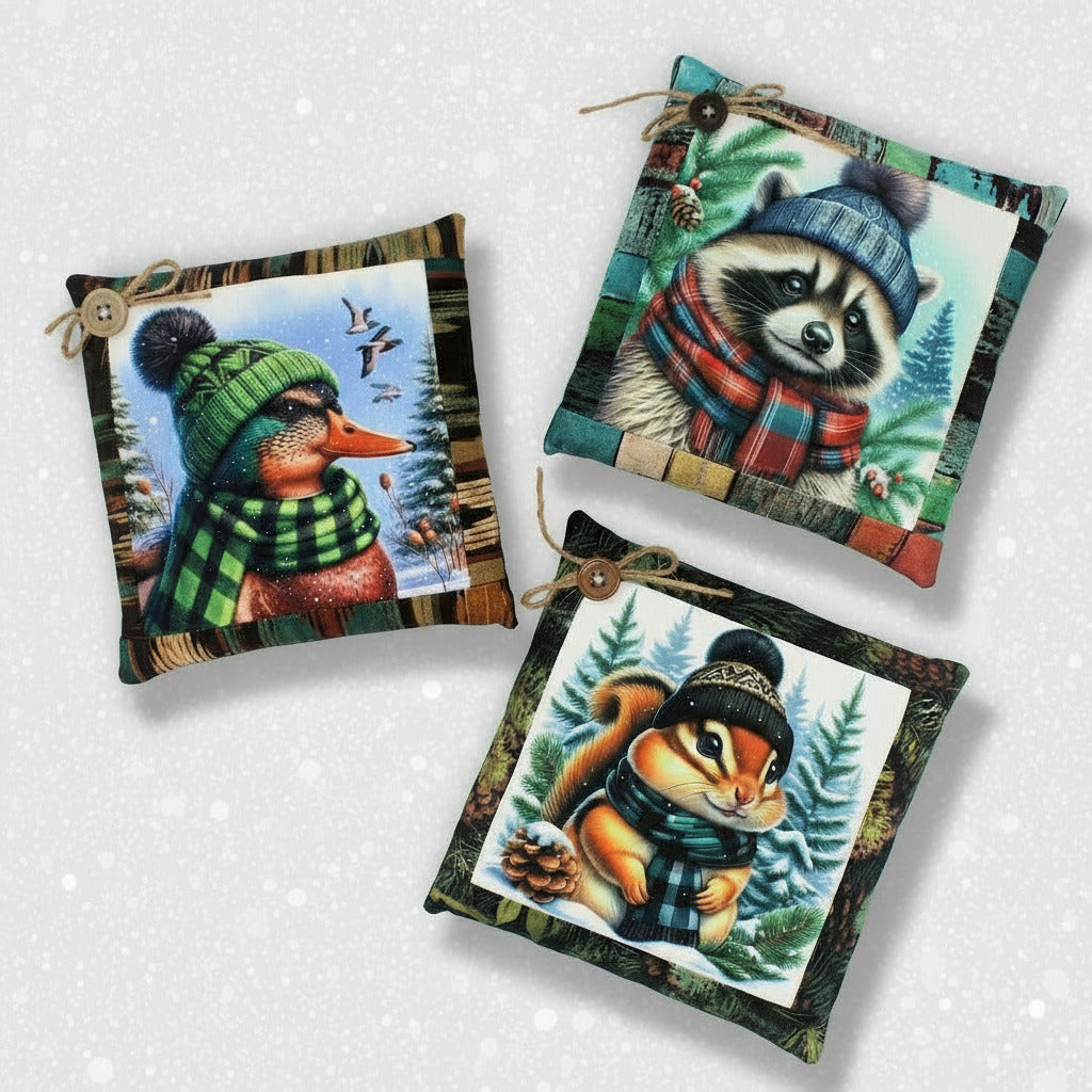 Three decorative pillows with animal illustrations wearing winter hats and scarves on a white background.