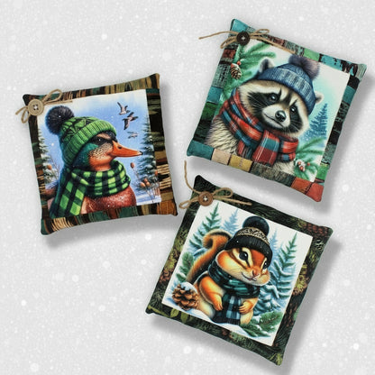Three decorative pillows with animal illustrations wearing winter hats and scarves on a white background.