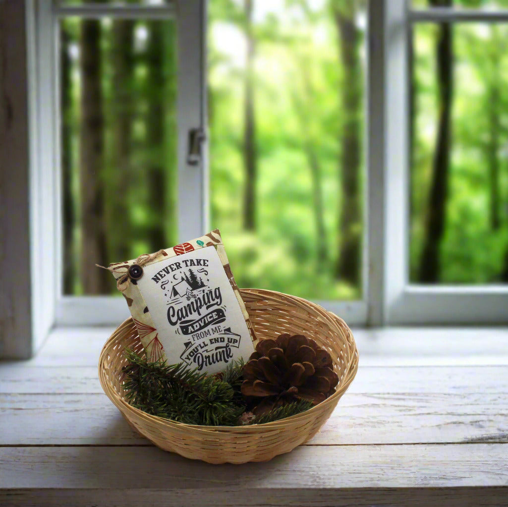 Decorative item with a sign in a woven basket on a wooden surface with a forest view.
