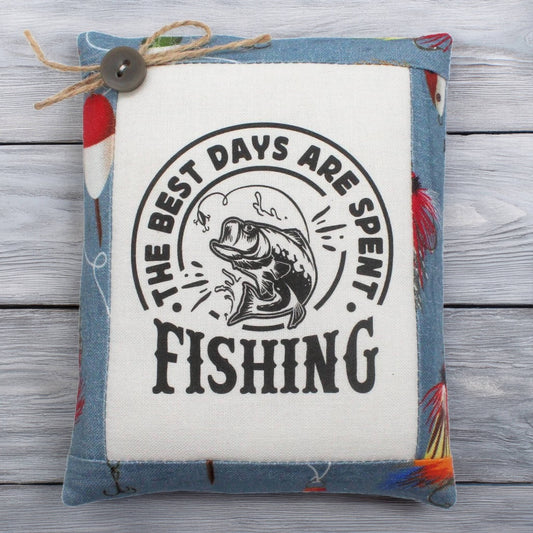 Decorative pillow tuck with fishing-themed text and graphics on a wooden surface