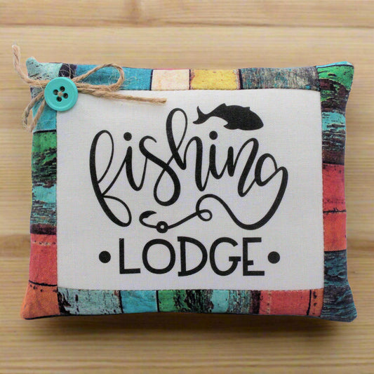 Colorful striped mini pillow bowl filler with 'Fishing Lodge' text on a wooden surface