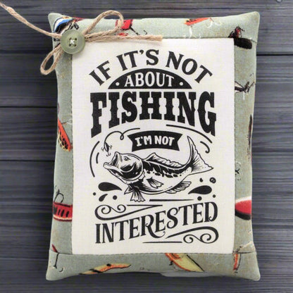 Small pillow tuck with fishing-themed text and graphic on a wooden surface