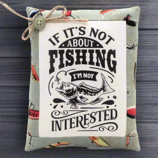 Small pillow tuck with fishing-themed text and graphic on a wooden surface