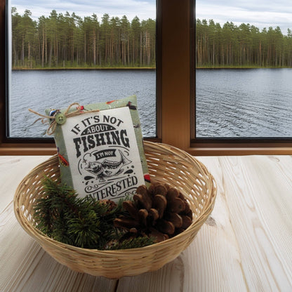 Decorative basket with a fishing-themed pillow and pinecones, set against a scenic lake view.