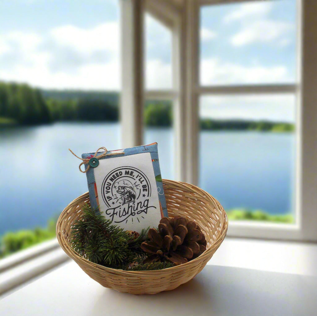 Small basket with fishing-themed packaging in a woven basket on a windowsill with a view of a lake.