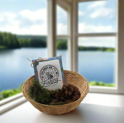 Small basket with fishing-themed packaging in a woven basket on a windowsill with a view of a lake.