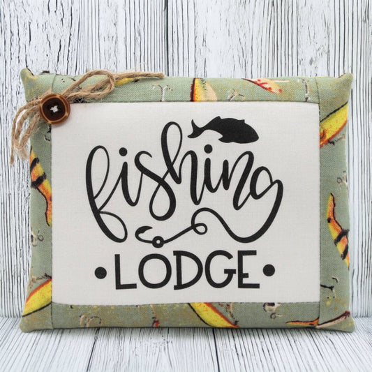 Decorative pillow tuck bowl filler with 'Fishing Lodge' text and fish design on a wooden background