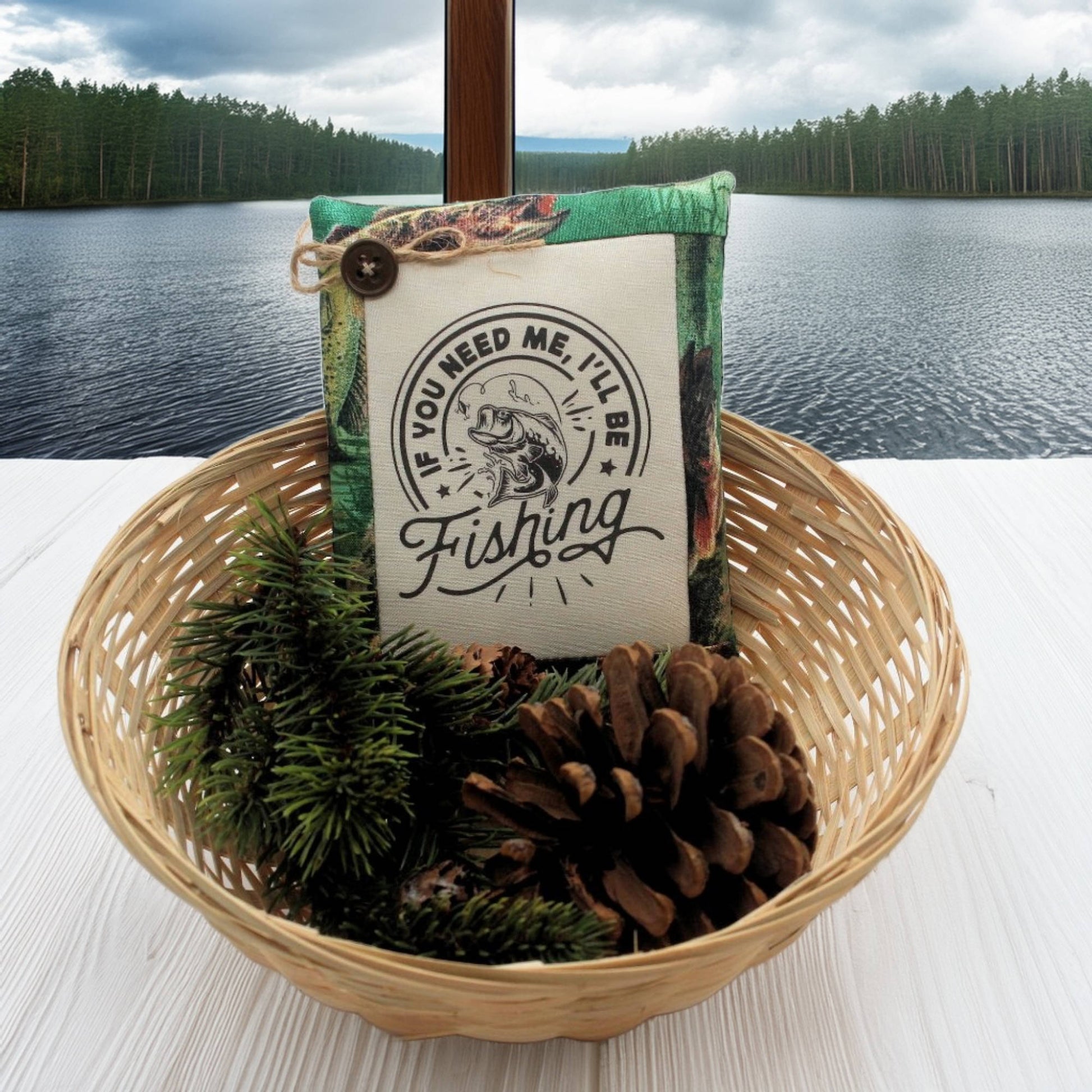 Decorative pillow with fishing theme in a basket by a lake
