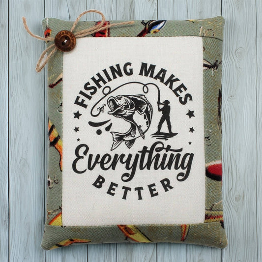 Decorative pillow tuck with fishing-themed text and graphics on a wooden surface