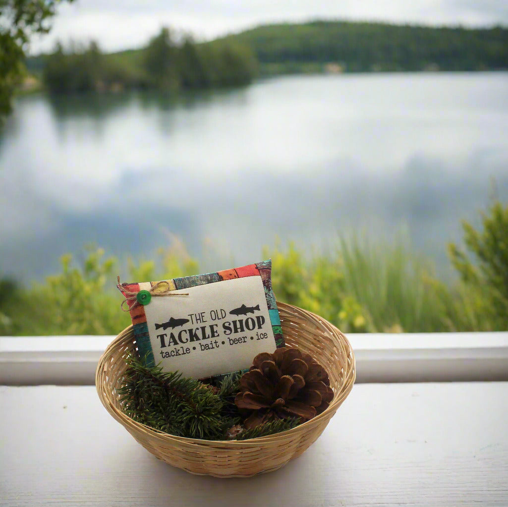 Bowl filler with 'The Old Tackle Shop' label in a woven basket against a scenic lake background