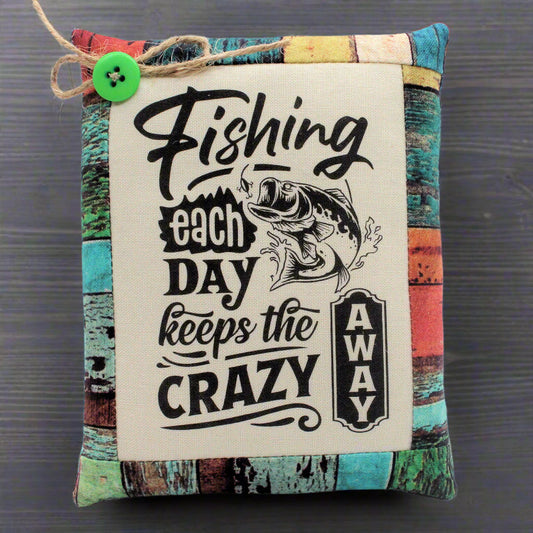 Decorative pillow tuck with fishing-themed text and graphic on a multicolored background
