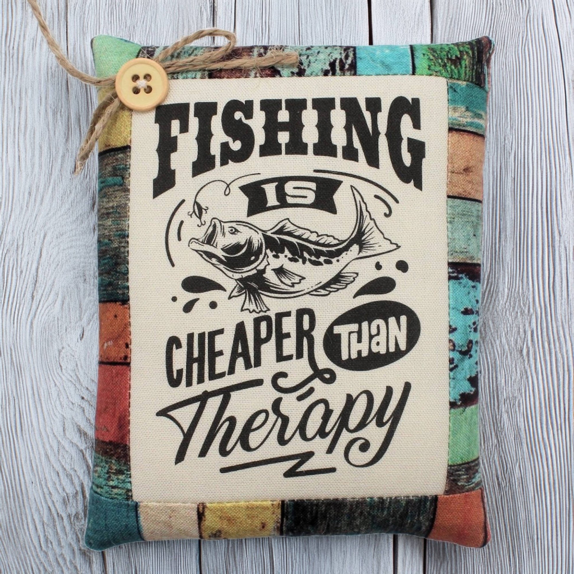 Decorative pillow tuck with fishing-themed text and button on a wooden surface