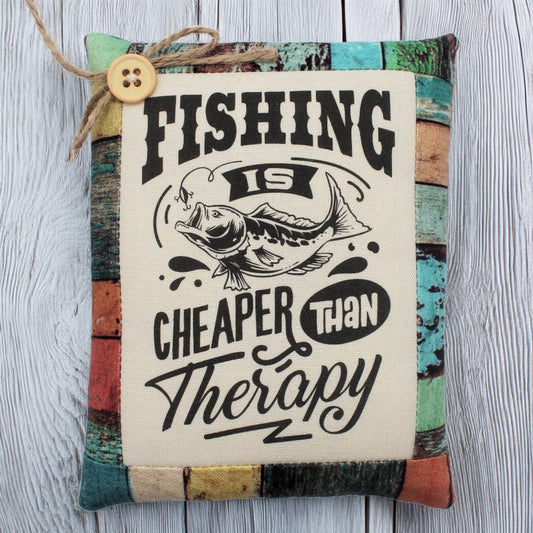 Decorative pillow tuck with fishing-themed text and button on a wooden surface