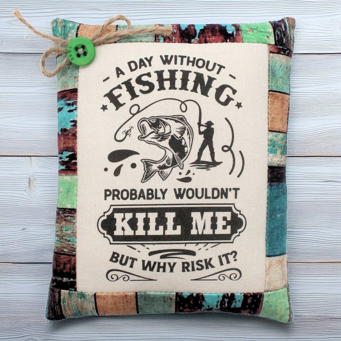 Decorative pillow tuck with fishing-themed text and graphics on a wooden surface