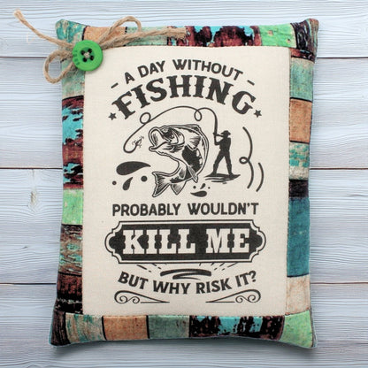 Decorative pillow tuck with fishing-themed text and graphics on a wooden surface