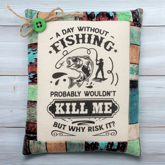 Decorative pillow tuck with fishing-themed text and graphics on a wooden surface
