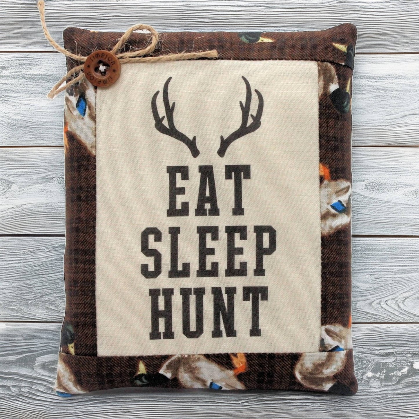 Pillow tuck with 'Eat Sleep Hunt' text and deer antlers on a wooden background