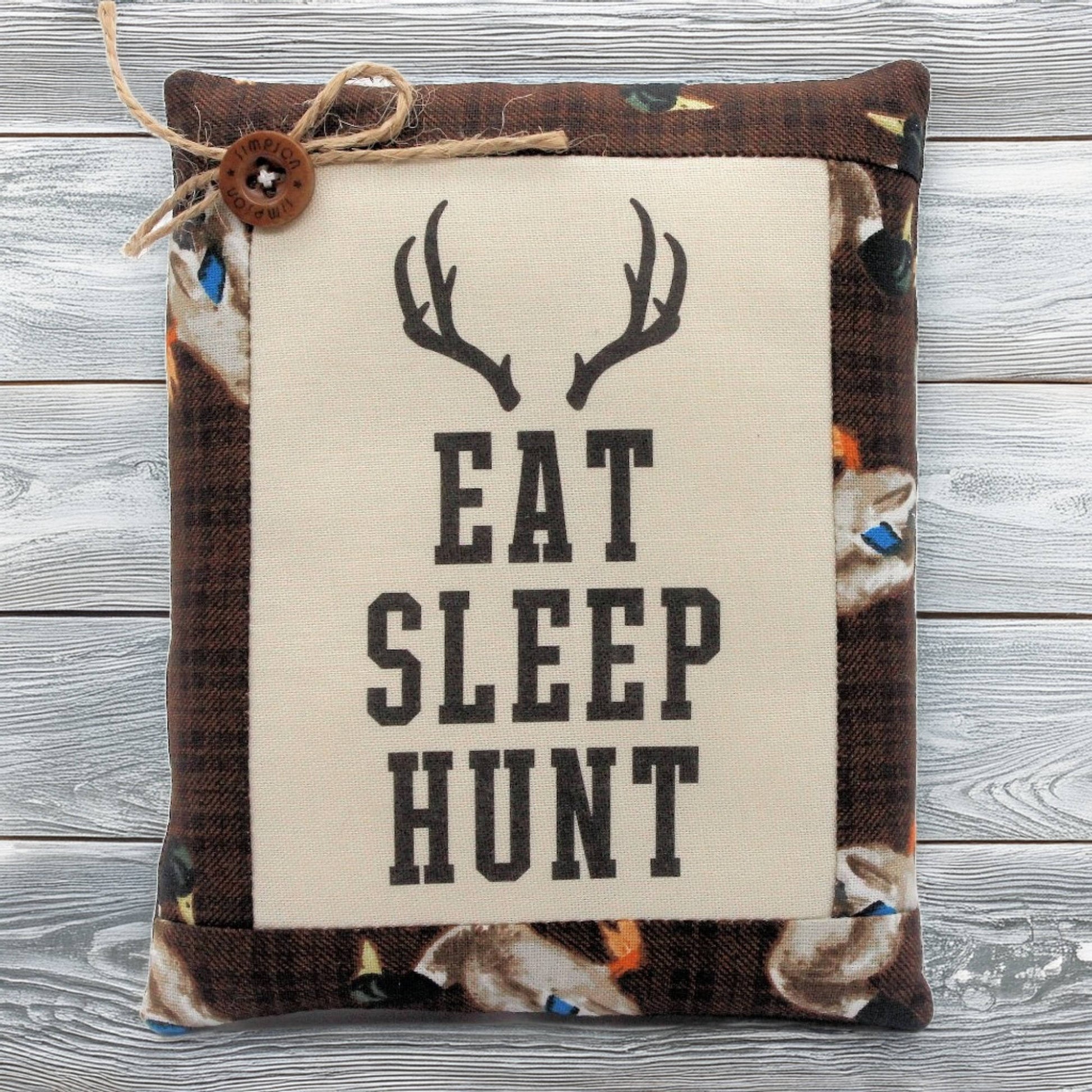 Pillow tuck with 'Eat Sleep Hunt' text and deer antlers on a wooden background