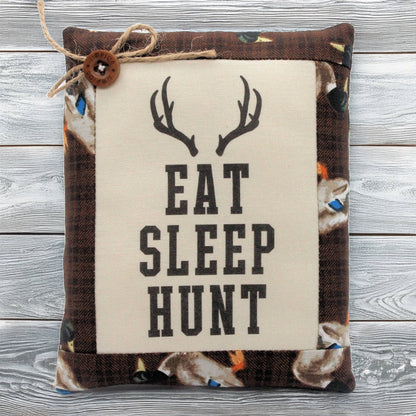 Pillow tuck with 'Eat Sleep Hunt' text and deer antlers on a wooden background