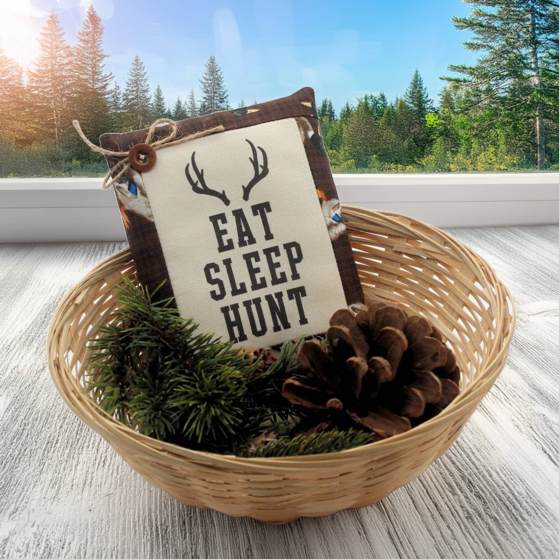 Decorative basket with a sign reading 'Eat Sleep Hunt' against a forest background