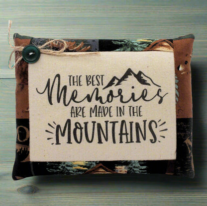 Pillow tuck with 'The best memories are made in the mountains' text and mountain graphic on a natural background.
