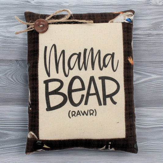 Small pillow with 'Mama Bear (Rawr)' text on a wooden surface