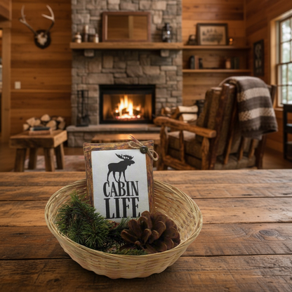 Decorative sign with 'Cabin Life' on a wooden table in a cozy cabin setting.