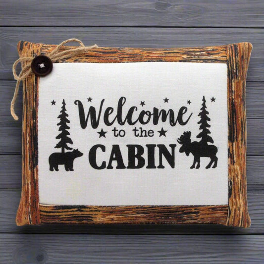 Decorative mini pillow bowl filler with 'Welcome to the Cabin' text and nature-themed illustrations on a wooden frame.
