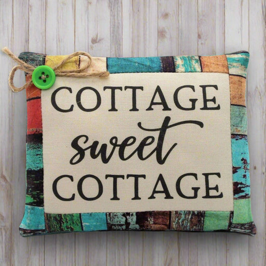 Decorative pillow tuck with 'Cottage sweet Cottage' text on a wooden background