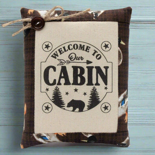 Decorative pillow tuck bowl filler with 'Welcome to Our Cabin' text on a wooden surface