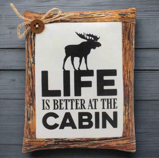 Decorative mini pillow sign with a moose silhouette and 'Life is Better at the Cabin' text on a wooden frame.