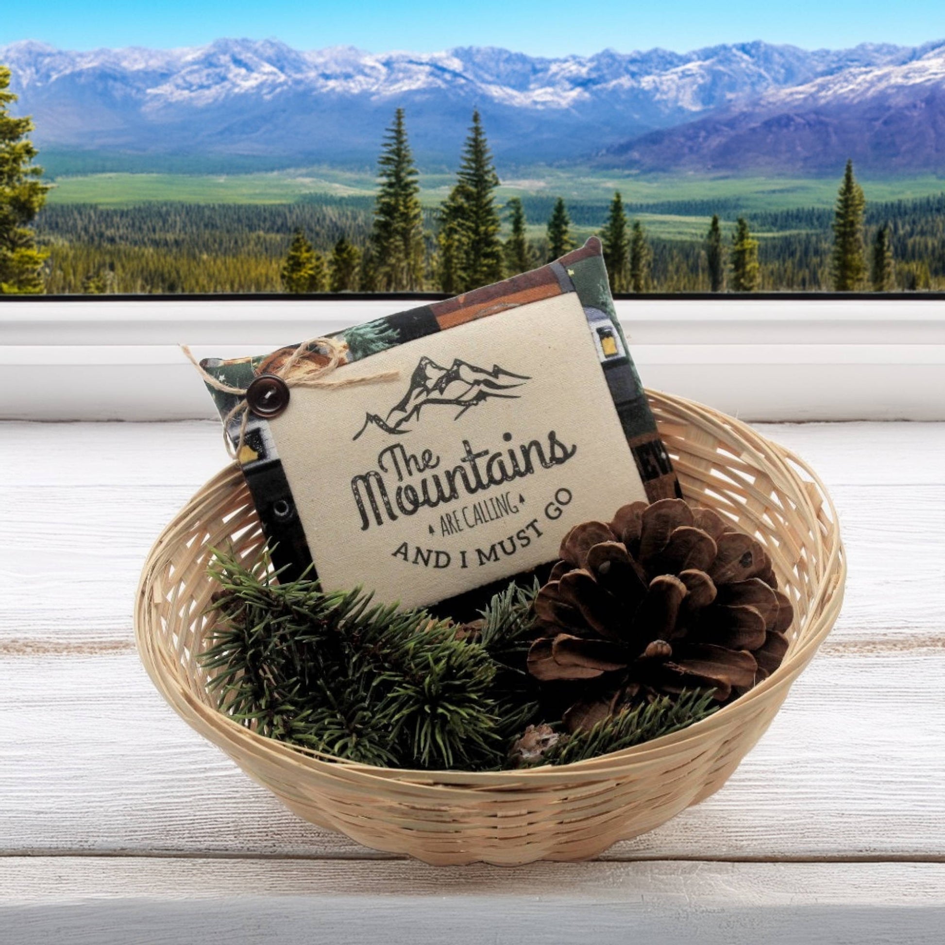 Decorative basket with pinecones and a sign in front of a mountain view
