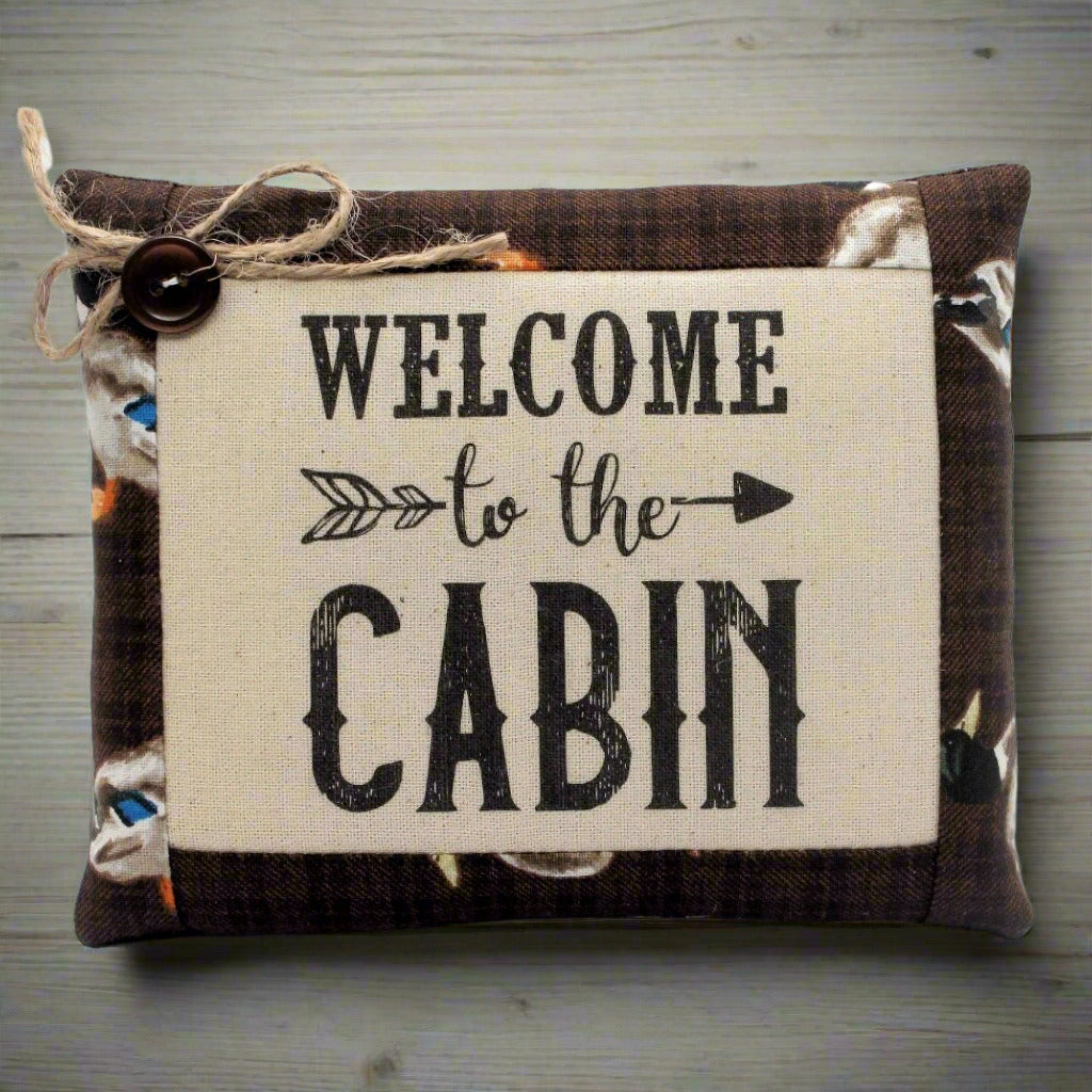Decorative pillow bowl filler with 'Welcome to the Cabin' text on a wooden surface