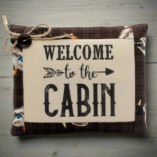 Decorative pillow bowl filler with 'Welcome to the Cabin' text on a wooden surface