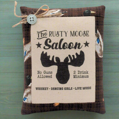 Decorative sign with 'The Rusty Moose Saloon' text and moose graphic on a wooden background.
