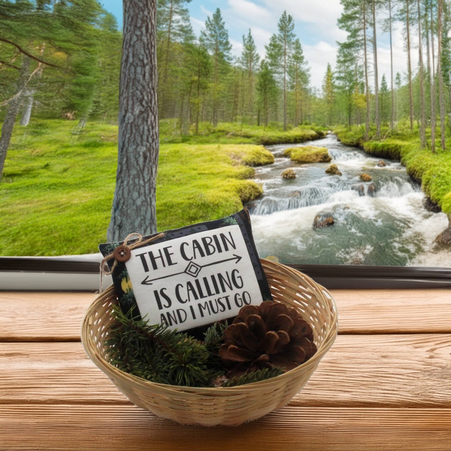 Decorative sign with 'The Cabin is Calling' text in a forest setting