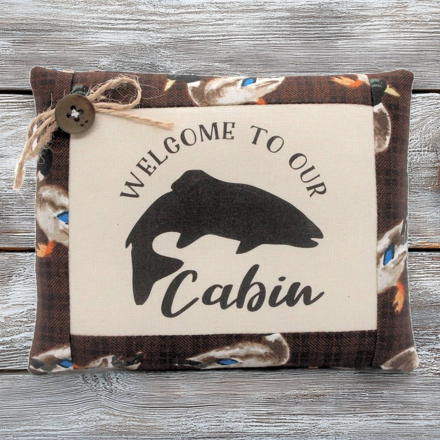 Decorative pillow tuck bowl filler with 'Welcome to our Cabin' text and fish silhouette on a wooden background