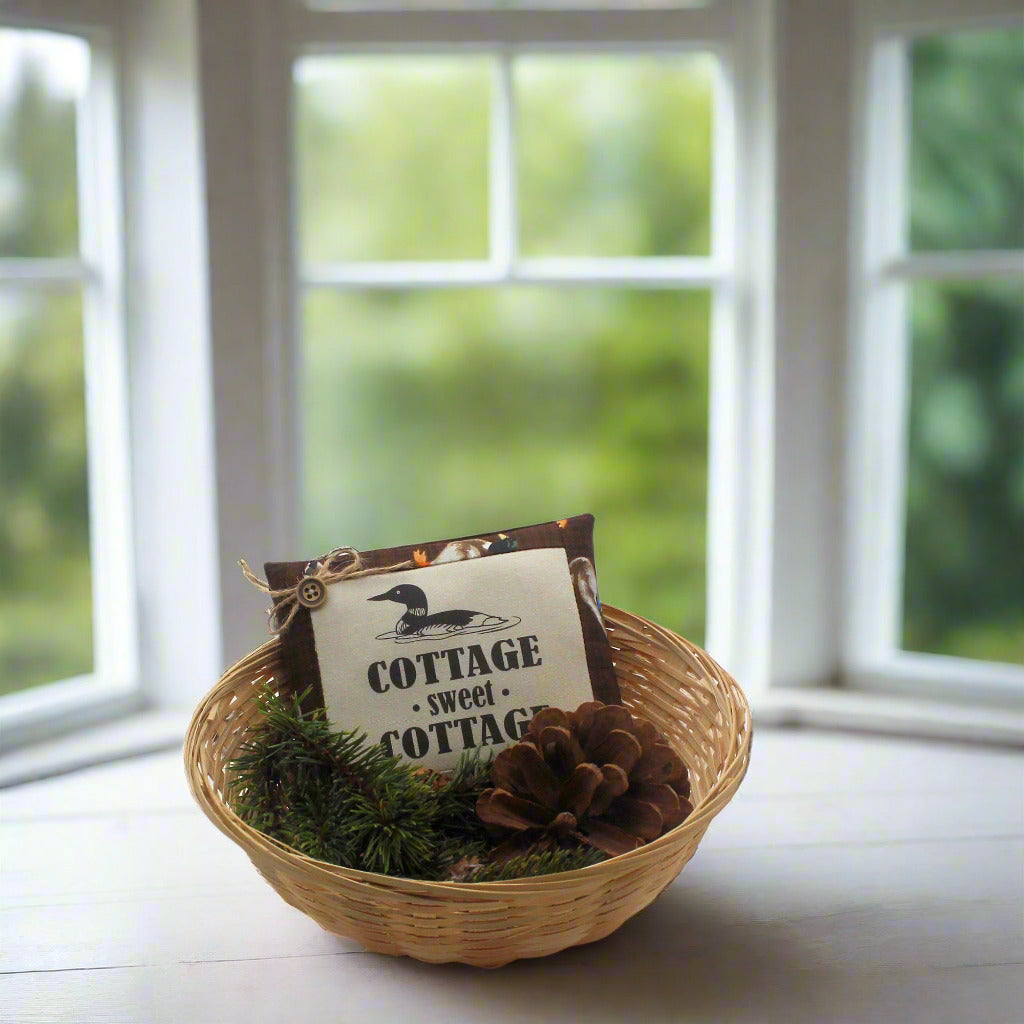 Decorative basket with a 'Cottage Sweet Cottage' sign on a windowsill.