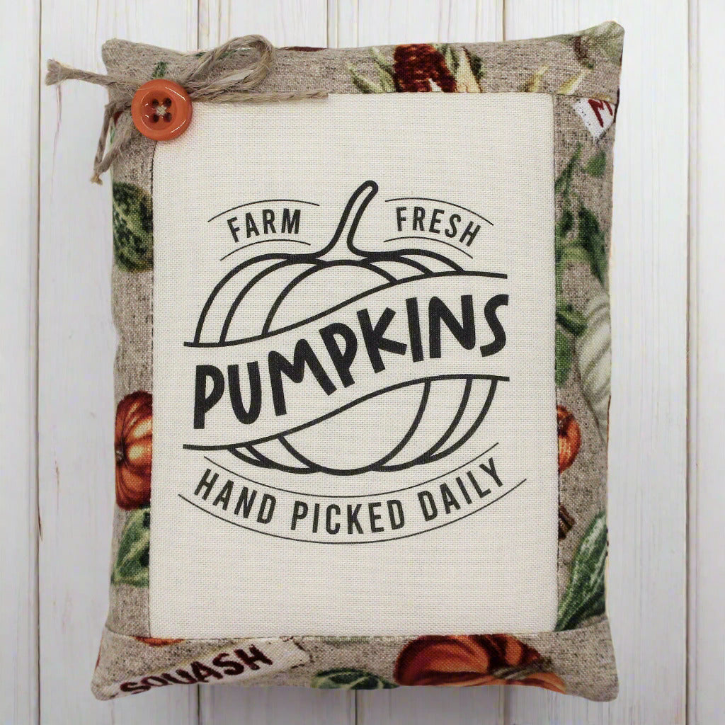 Decorative pillow tuck with pumpkin design and text on a wooden background